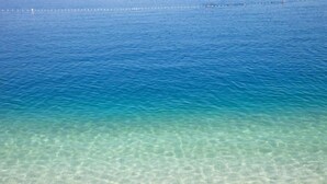 A clear view of a beach with a sandy shore and calm water. - Beach rooms Riviera (Makarska)