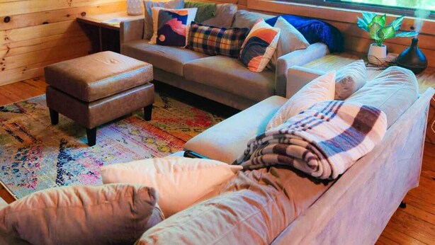 A cozy cabin interior with a sofa, ottoman, and a lamp. - Cozy Cabin in Nantahala Village (Bryson City)
