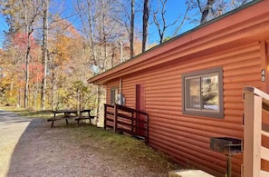 Een chalet met een houten gevel, een picknicktafel en een brievenbus.