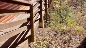 A wooden cabin with a wooden deck and a stone wall. - Cozy Cabin in Nantahala Village (Bryson City)