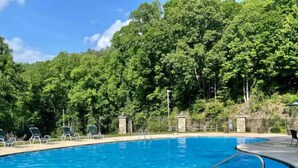 A swimming pool with clear blue water, surrounded by a concrete deck and metal pool ladders. - Cozy Cabin in Nantahala Village (Bryson City)