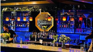A bar area with shelves of bottles, a central decorative wall, and blue lighting. - Cozy Cabin in Nantahala Village (Bryson City)