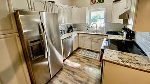 A kitchen with white cabinets, stainless steel appliances, and a wooden floor. - TC TWO OAKS Home / Minutes walk to Downtown & Beach (Traverse City)