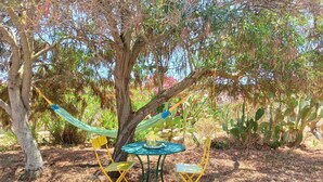 Un albero con un'amaca e due sedie gialle disposte attorno a un tavolino.