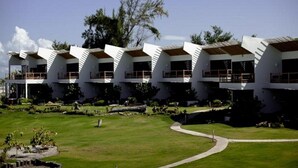 A row of modern, white buildings with flat roofs and balconies, surrounded by well-maintained lawns and trees. - Nitro City Panama Action Sports Resort (Punta Chame)