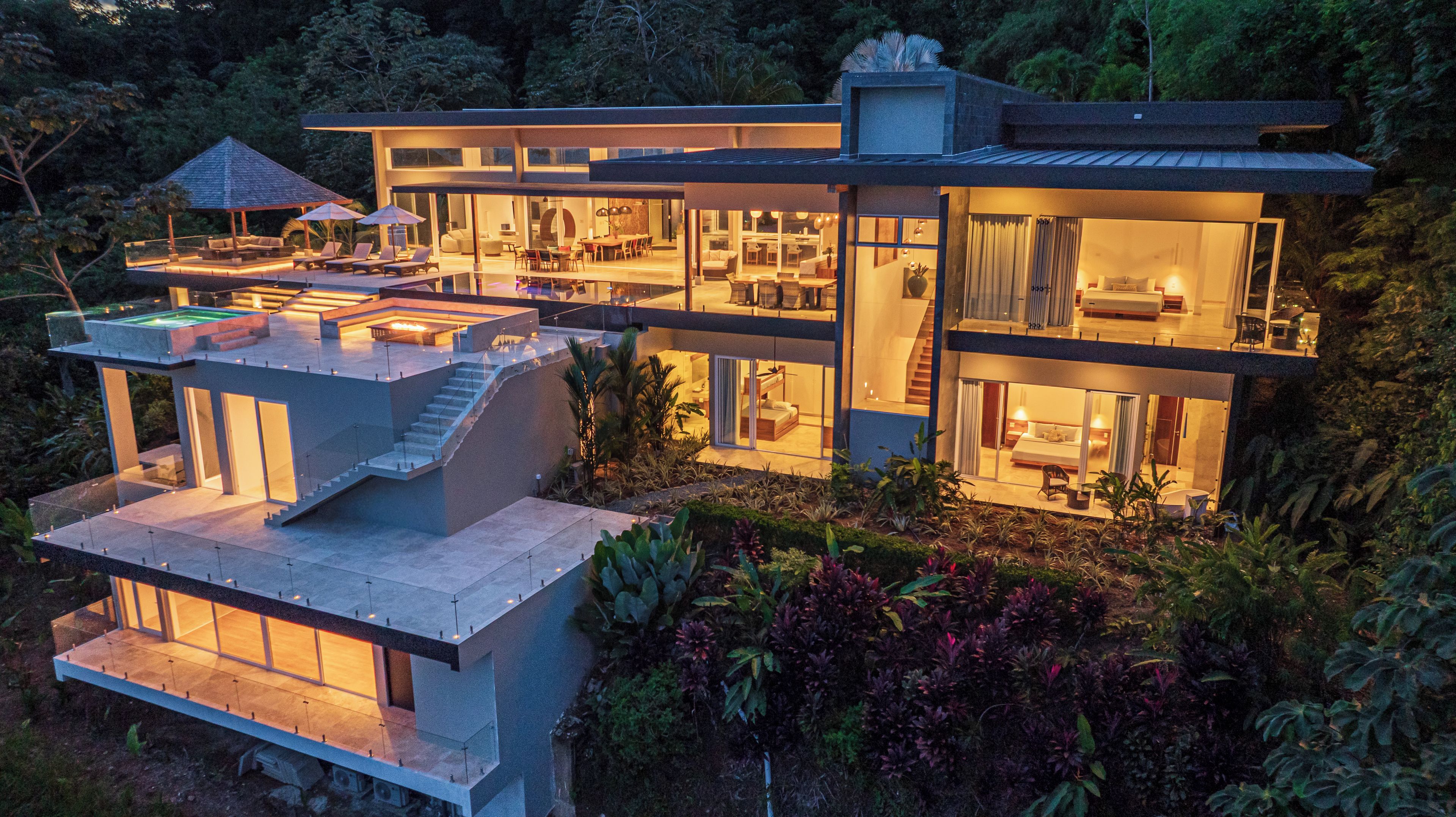 A modern multi-story house with a rooftop pool, large glass windows, and a well-maintained garden.