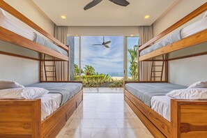 A hotel room with two bunk beds, a ceiling fan, and a view of the beach. - Ombak Luxury House- 5 bedroom Home / Concierge (Uvita)