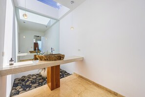 A modern bathroom with a large mirror, a stone sink, and a skylight. - Ombak Luxury House- 5 bedroom Home / Concierge (Uvita)