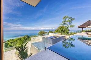 Ein moderner Infinity-Pool mit freiem Blick auf den Ozean und einer von Bäumen gesäumten Terrasse.