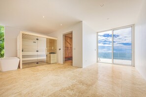 Ein modernes Interieur mit einer Glastür, die auf einen Balkon mit Meerblick führt.