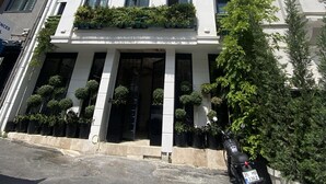 Un edifici de diversos pisos amb balcons, una entrada central i una moto aparcada.