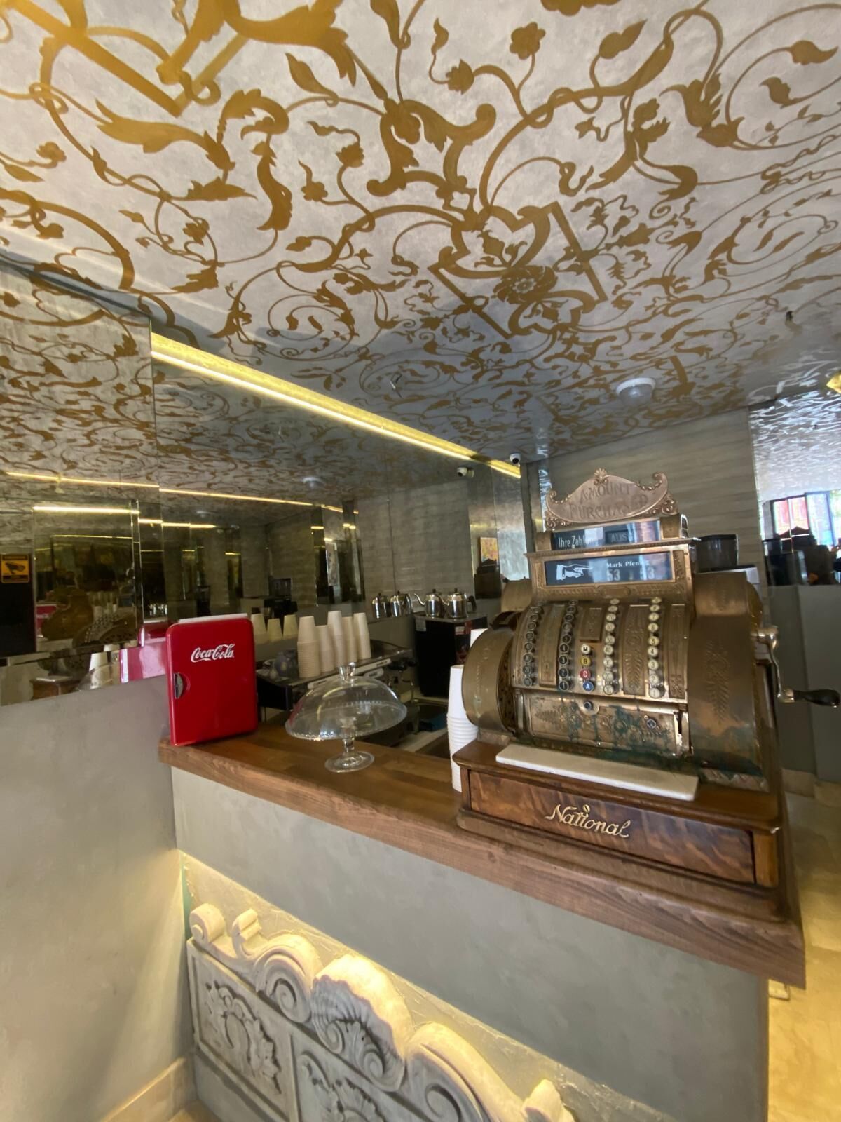 A bar area with a vintage jukebox, a Coca-Cola cooler, and a decorative ceiling.