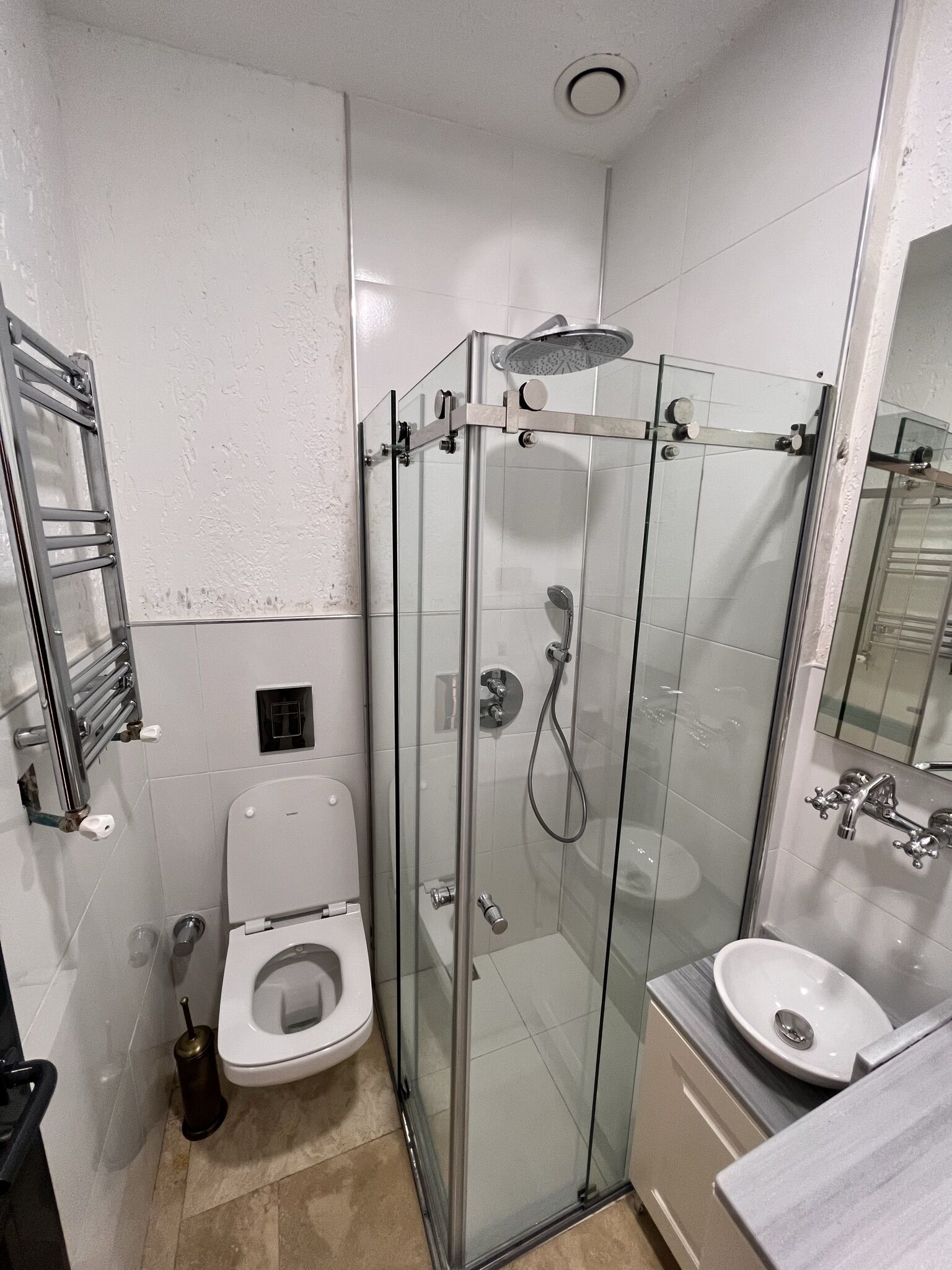 A small, modern bathroom with a glass-enclosed shower, a toilet, and a sink.