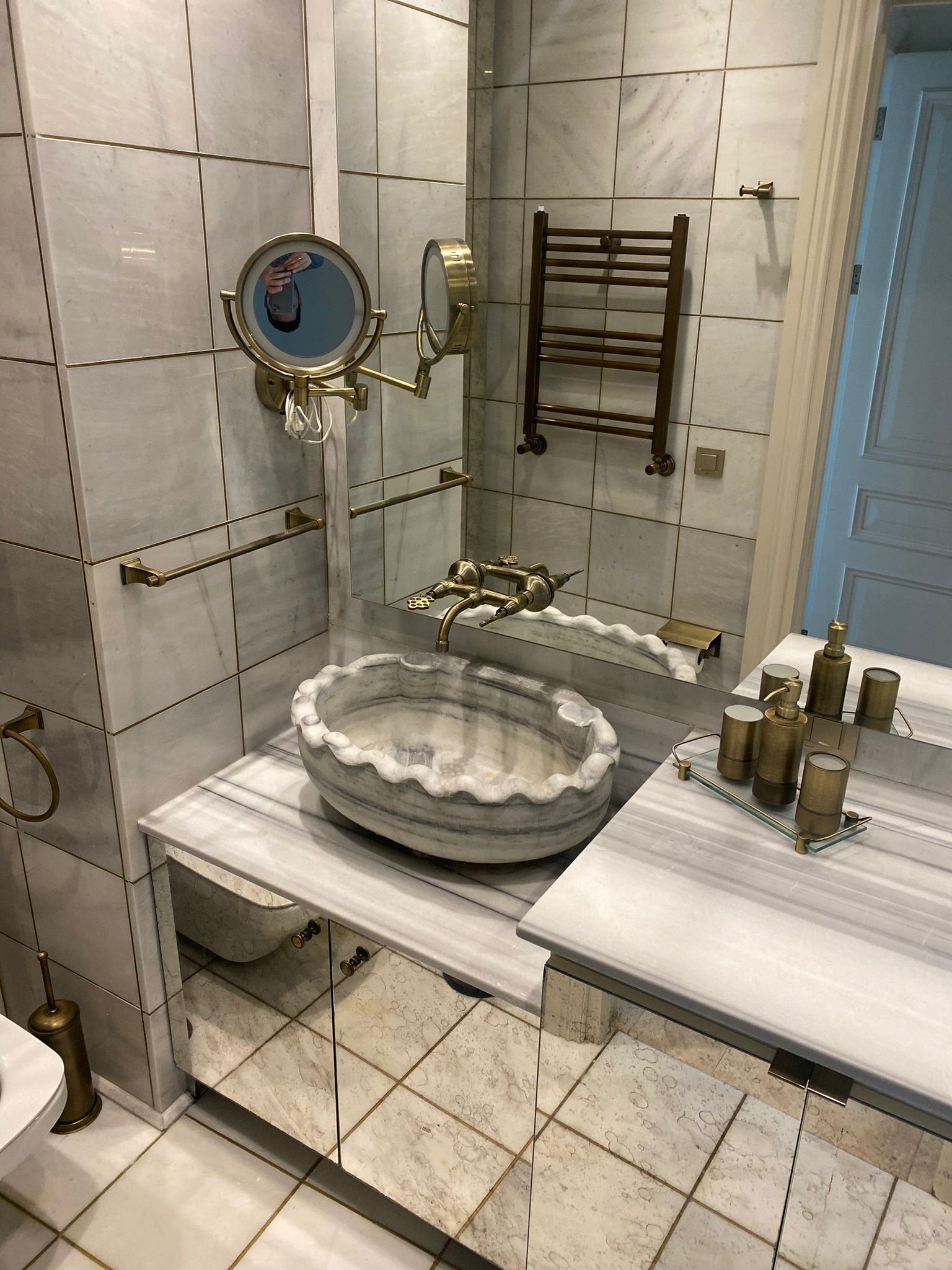 Un baño con lavamanos de mármol, un espejo, toallero y un inodoro.