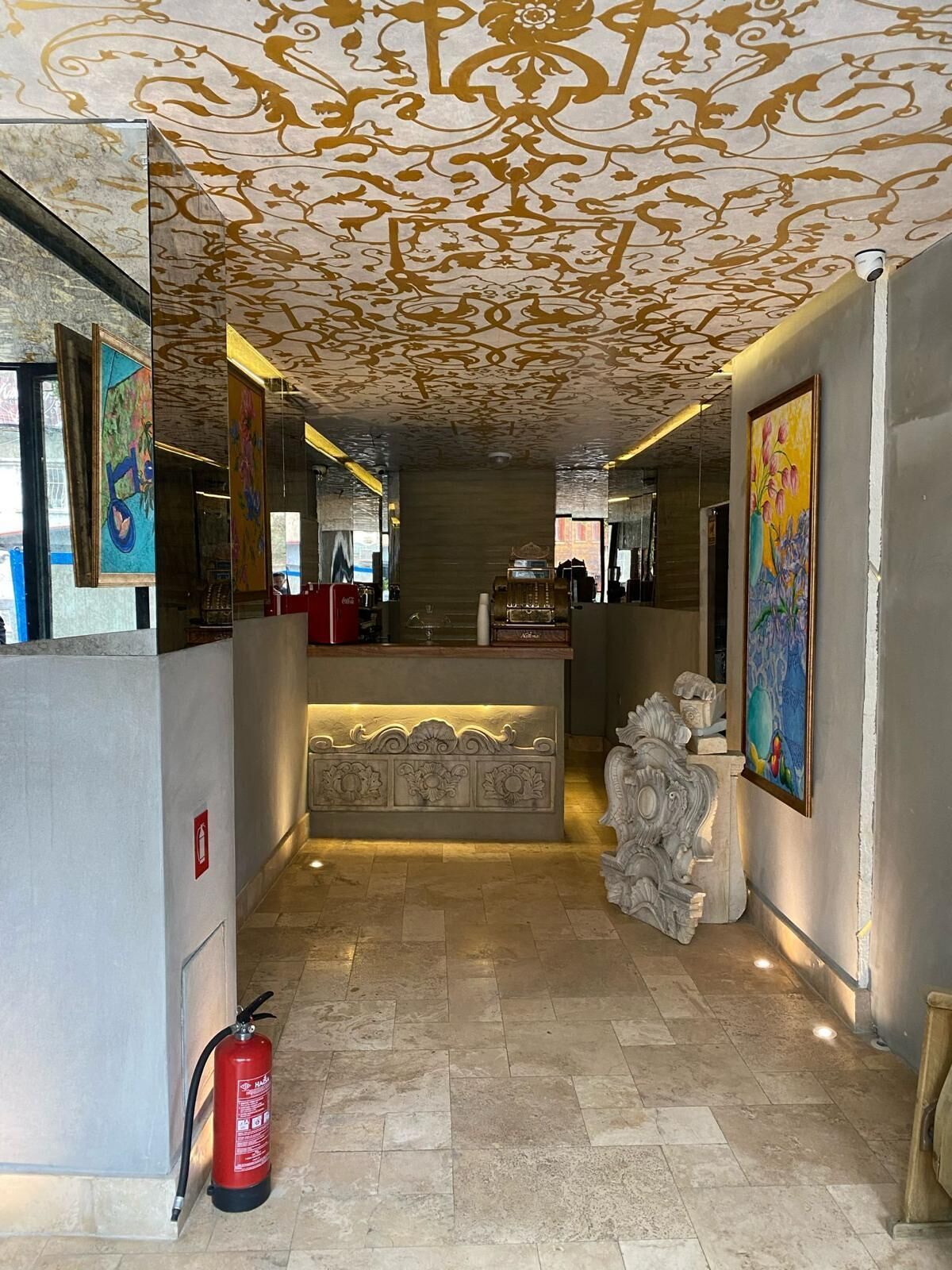 En lobby med et mønstret loft, en receptionsdisk og en brandslukker.