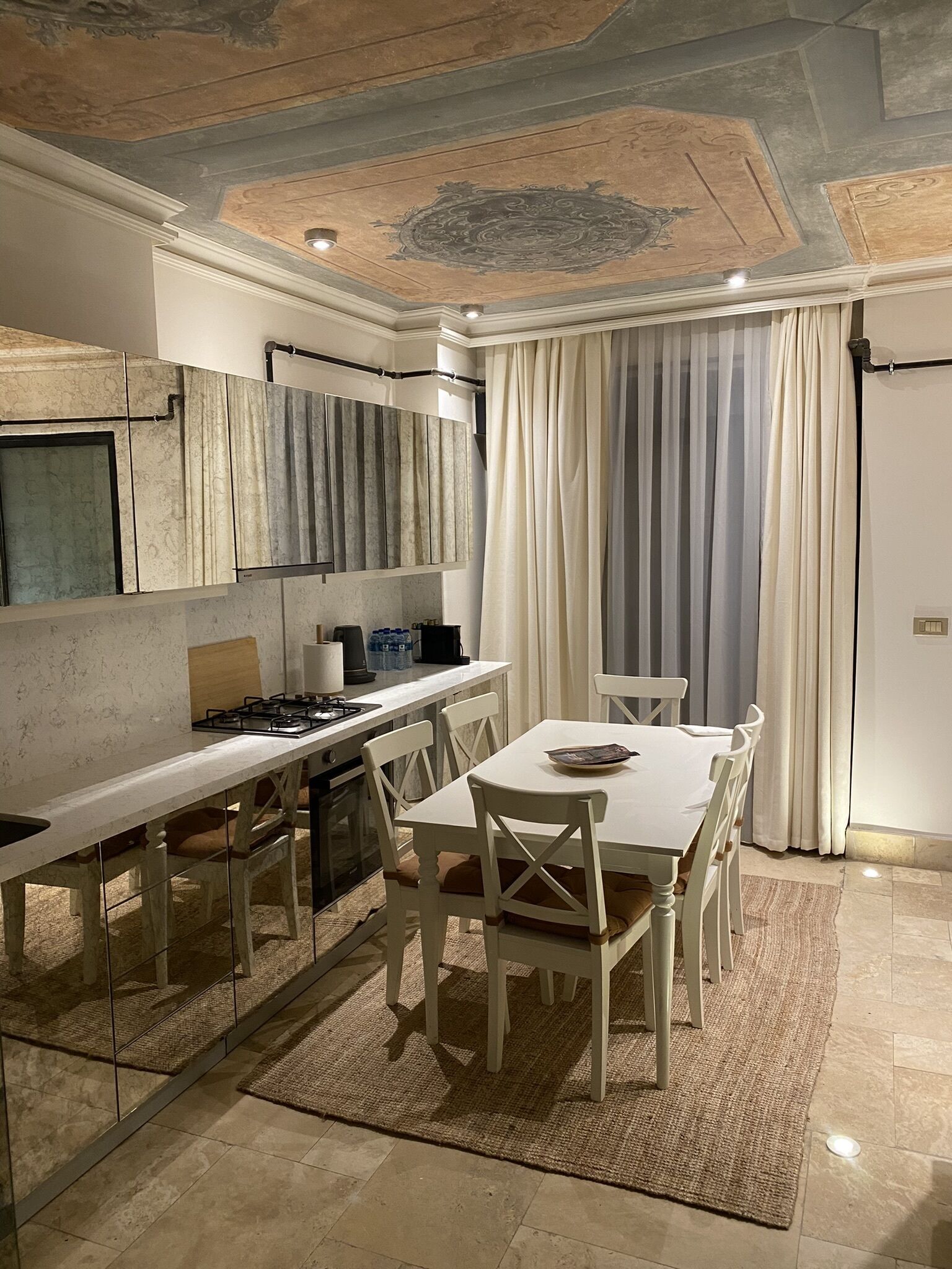 A modern kitchen with a central island, white cabinetry, and a dining area with a table and chairs.