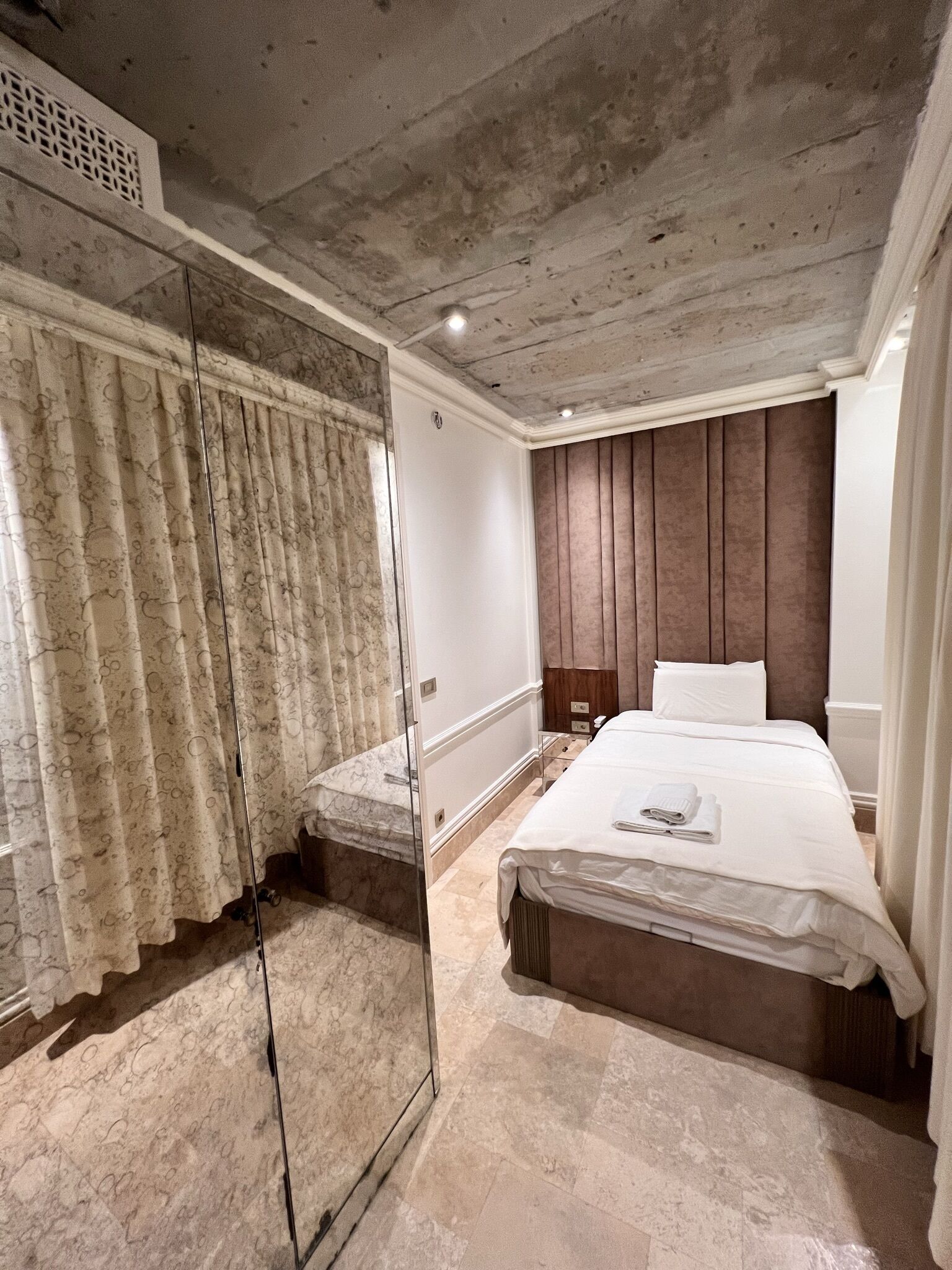 A bedroom with a large bed, a glass shower enclosure, and a wooden headboard.