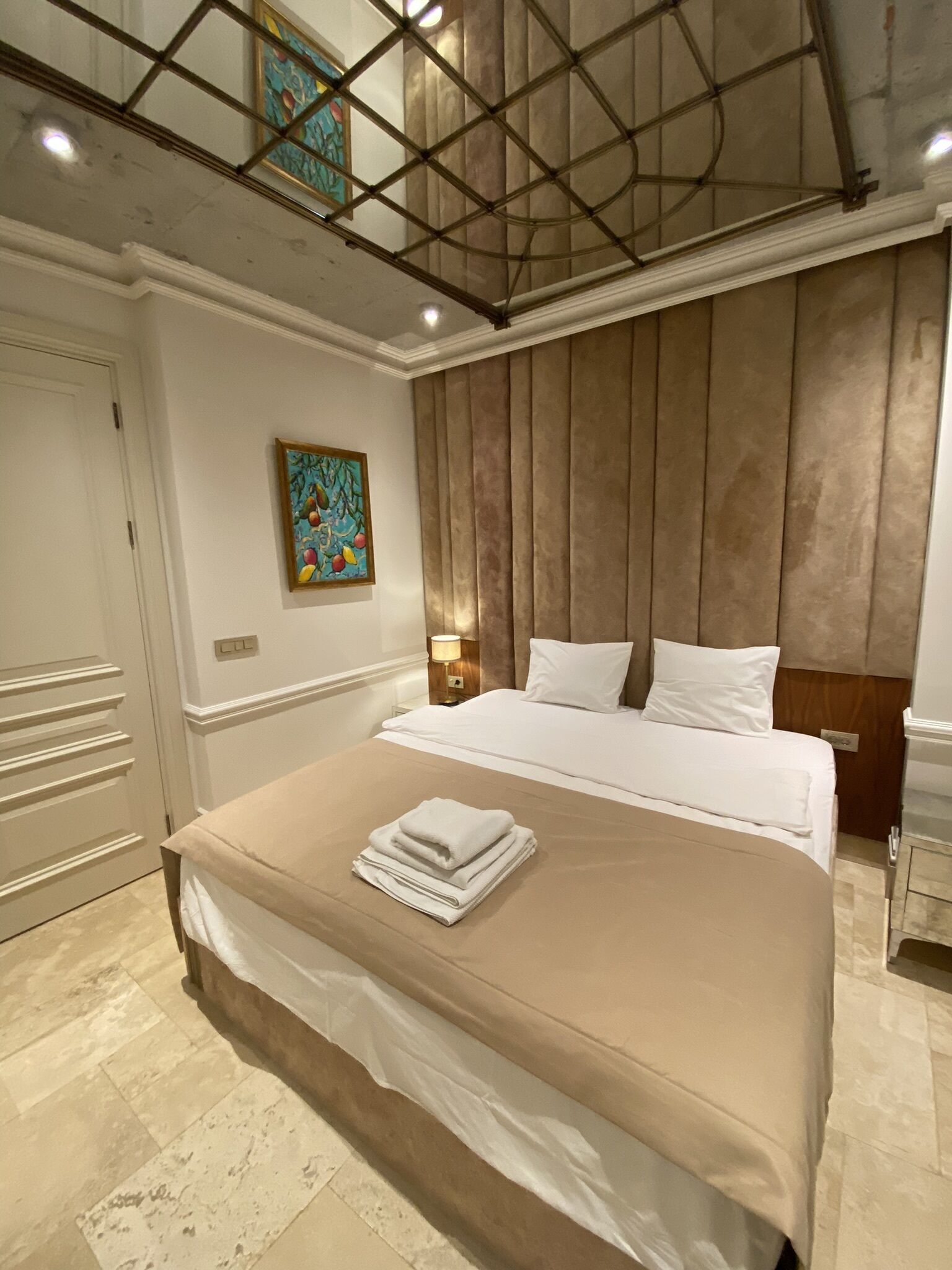 Una habitación de hotel con una cama grande, un cuadro en la pared y un techo con diseño de cuadrícula.