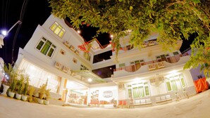 A multi-story building with balconies, a ground-level shop, and potted plants. - Ostello Bello Nyaung Shwe (Nyaungshwe)