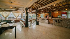 A reception area with a reception desk, a travel desk, and a seating area with tables and chairs. - Ostello Bello Nyaung Shwe (Nyaungshwe)