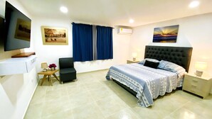 Een slaapkamer met een bed, een stoel, een televisie en kunstwerken aan de wanden.