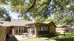 A house with a covered patio, a fenced backyard, and a large tree providing shade. - Sprawling Ranch Home (Fort Worth)