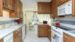 A kitchen with wooden cabinets, a white stove, a microwave, and a sink. - Sprawling Ranch Home (Fort Worth)
