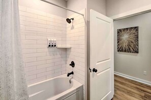 A bathroom with a bathtub, a showerhead, and a towel rack. - Lakefront Retreat in Lake Hamilton (Lake Hamilton)