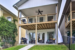 Un bâtiment à deux étages doté d’un patio couvert, d’un espace extérieur aménagé avec des sièges et d’un ventilateur de plafond.