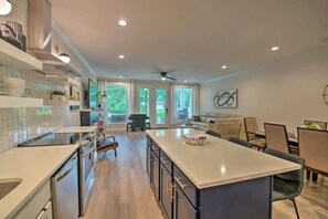A modern kitchen with a central island, a dining area with a table and chairs, and a living space with a sofa and a coffee table. - Lakefront Retreat in Lake Hamilton (Lake Hamilton)