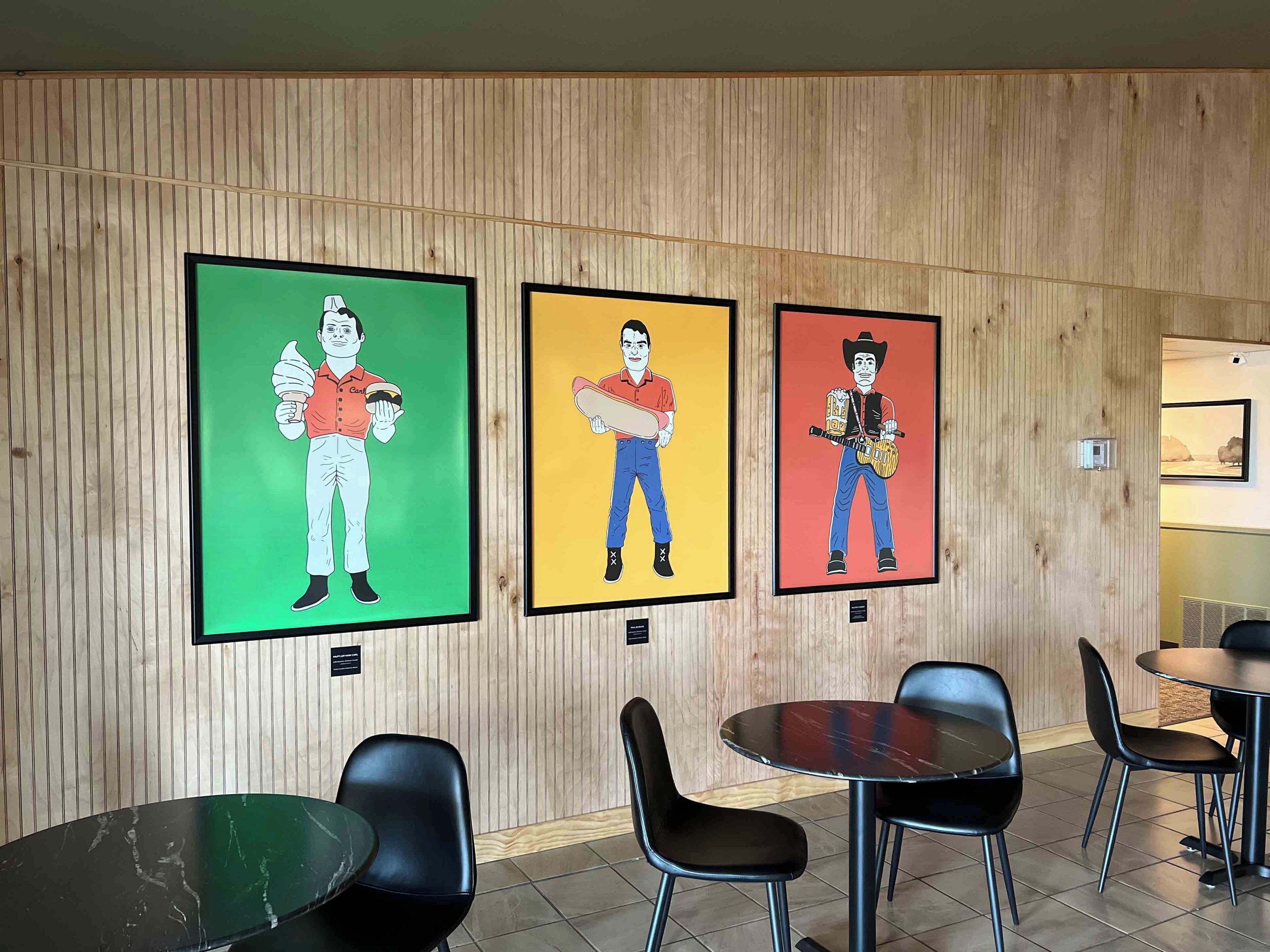 Una habitación con tres cuadros enmarcados en la pared, una mesa redonda y sillas negras.