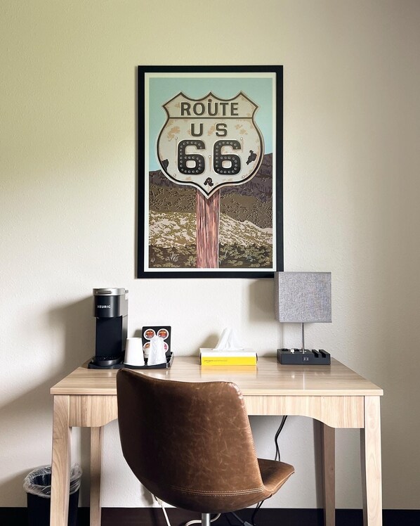 A desk with a coffee maker, a lamp, a tissue box, and a framed Route 66 sign.