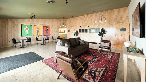 Un salon moderne avec un canapé, des fauteuils, une table basse et un tapis à motifs.