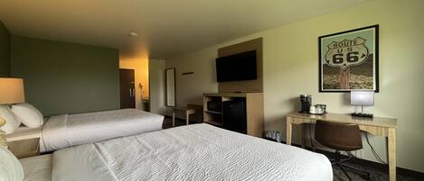 Une chambre d’hôtel avec deux lits, un bureau avec une chaise, une télévision, une machine à café et un panneau indiquant la Route 66.