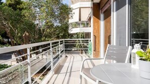 Un balcon avec une balustrade blanche, une table avec une chaise et une plante en pot.