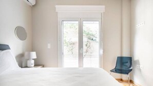 Une chambre à coucher comprenant un lit, une table de chevet, une lampe, une chaise et une fenêtre donnant sur un paysage verdoyant.
