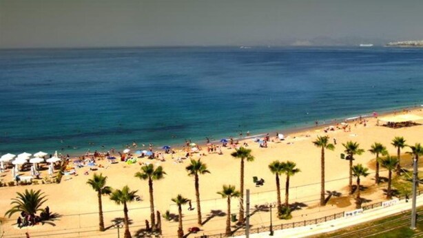 Une plage avec des palmiers, des parasols et des gens.