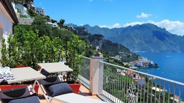 A balcony with two sun loungers, a small table, and a potted plant.