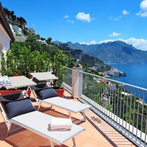 A balcony with two sun loungers, a small table, and a potted plant. - Amalfi Blu Retreat  (Amalfi)