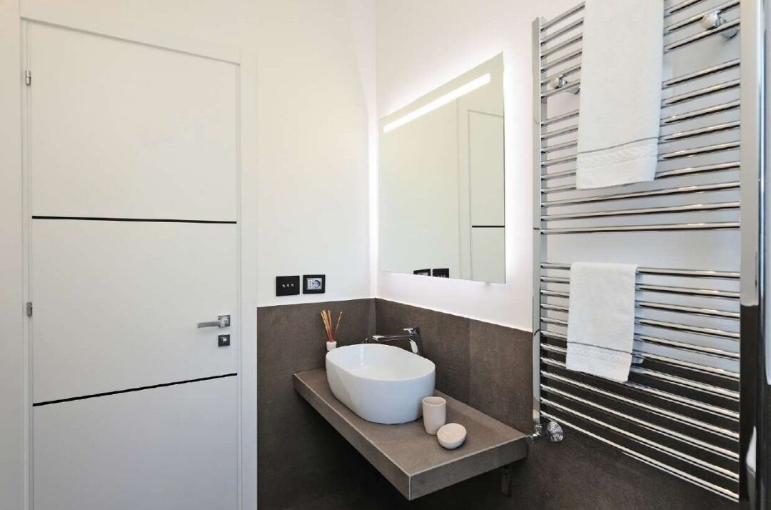A modern bathroom with a white sink, dark floor, and a towel rack with multiple towels.