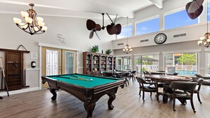 A spacious room with a pool table, a large bookshelf, and a dining area with chairs. - Cozy Condo at Village Brooks (Sarasota)