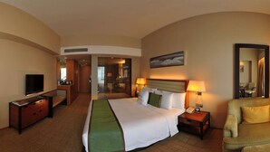 A hotel room with a bed, bedside table, lamp, chair, TV, and a desk with a mirror. - Grand Metropark Hotel Kunshan (Suzhou)