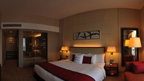 A hotel room with a large bed, two bedside lamps, a mirror, and a painting on the wall. - Grand Metropark Hotel Kunshan (Suzhou)