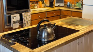 Une cuisine avec des meubles de rangement en bois, une cuisinière, une bouilloire et un four à micro-ondes.