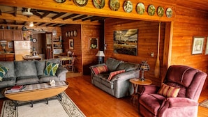L’intérieur chaleureux d’un chalet avec des murs en bois, un coin repas et un salon meublé de canapés et d’une table basse.