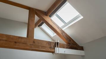 A room with exposed wooden beams, a skylight, and a white ceiling.