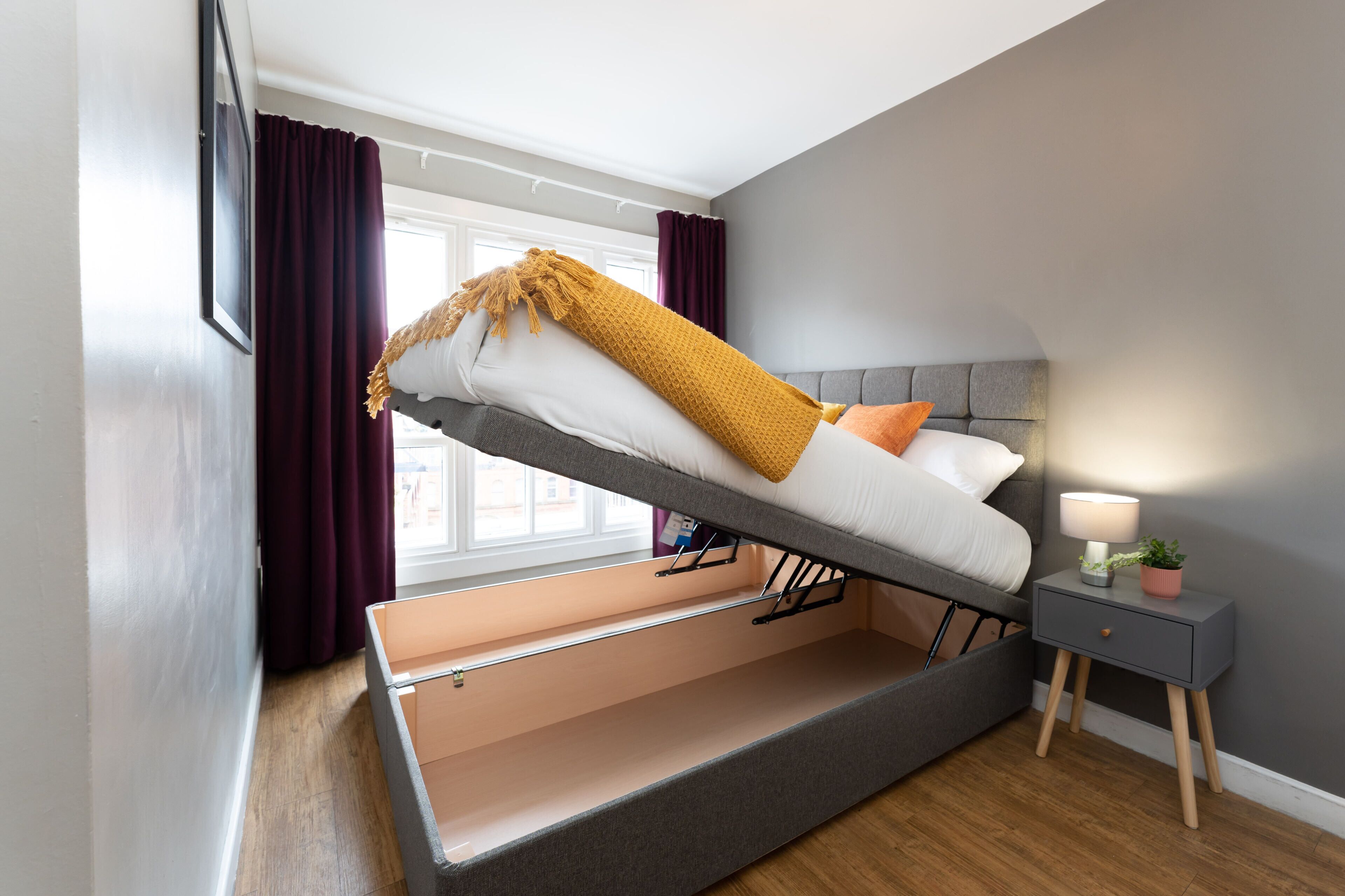 Une chambre de style loft moderne, avec un lit, une table de chevet et une fenêtre avec des rideaux.