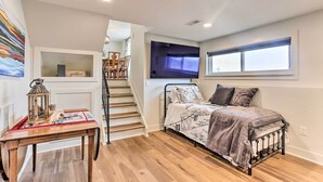 A bedroom with a bed, a TV, a window, a staircase, and a table with a lantern. - 2 Mi to Dtwn Castle Rock: Home w/ Furnished Patio (Castle Rock)