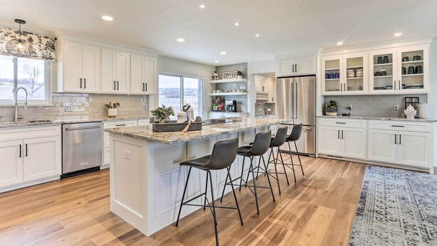 A modern kitchen with white cabinetry, a central island with bar stools, a built-in refrigerator, and a view of the outdoors. - 2 Mi to Dtwn Castle Rock: Home w/ Furnished Patio (Castle Rock)