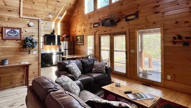 Een gezellig chalet interieur met houten details, een bank, een bijzettafeltje en een keukenhoek.
